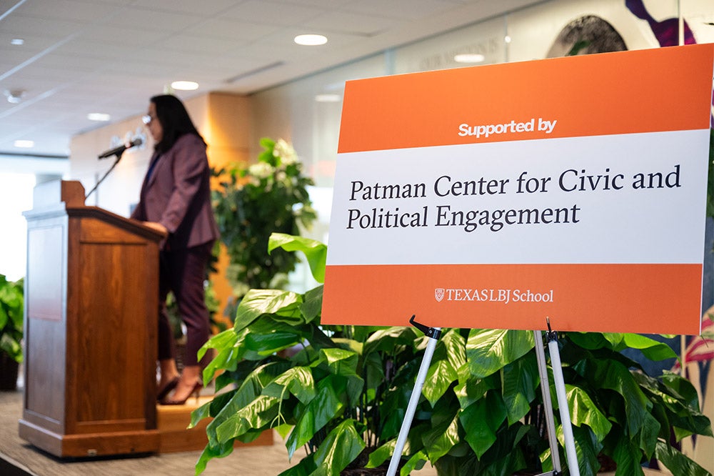 speaker at podium with conference poster in foreground