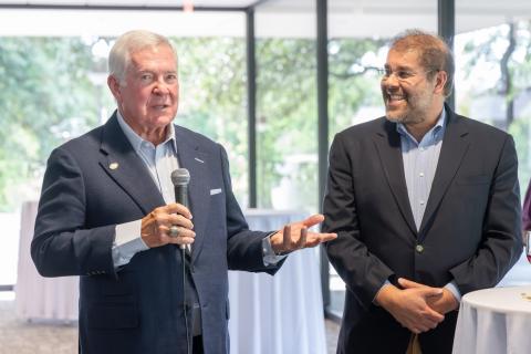 Coach Mack Brown giving a speech, while a professor stands to the side.