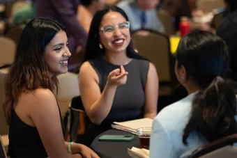 woman pointing across table at another woman